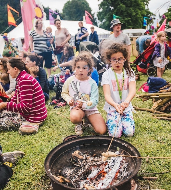 Two children kneeling in front of a festival campfire
